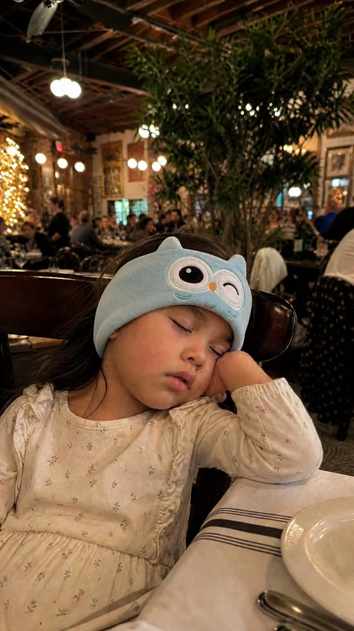 Girl fast asleep at a restaurant wearing a blue owl Hushaboo