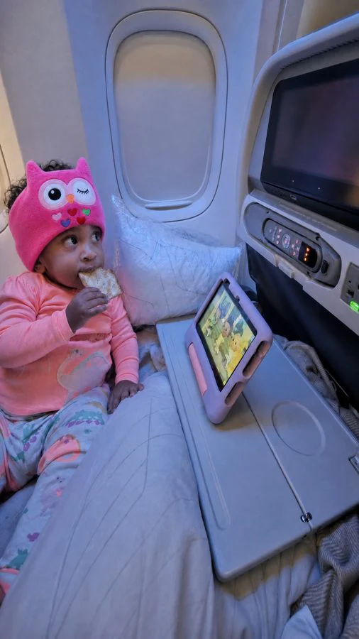 Little one relaxed on a plane wearing a pink owl Hushaboo